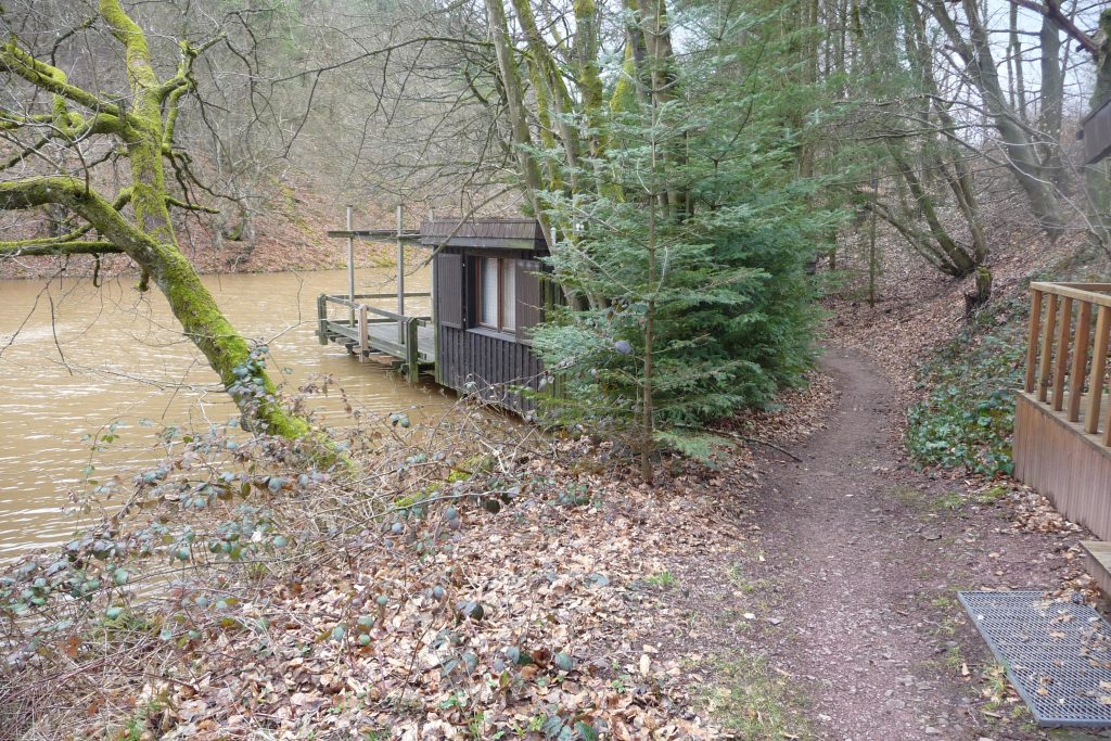 Ein See im Wald, Mittelgebirgsregion, mit Hütte am Weg und Steg zum See